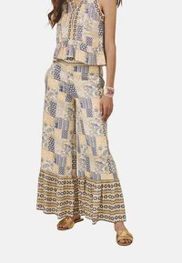 Conjunto de dos piezas que incluye una blusa sin mangas con estampado y pantalones sueltos de pierna ancha. La tela es ligera con colores amarillos, azules y diseños florales.