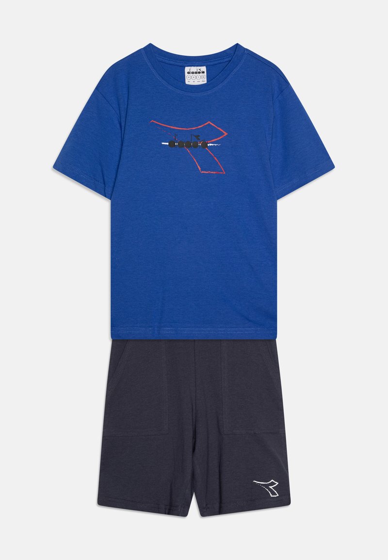 Zila kokvilnas T-krekls ar sarkano kontūru dizainu un melno grafiku; saskaņots ar tumši pelēkiem šortiem, kas aprīkoti ar divām kabatām un baltu logotipa akcentu.