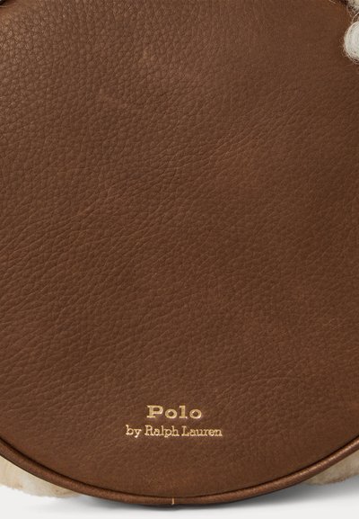 Ruskea nahkainen pyöreä laukku, jossa on teksturoitu pinta ja kultainen, painettu logo, jossa lukee "Polo by Ralph Lauren." Sileät reunat.