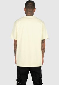 Geel katoenen t-shirt met korte mouwen en een ronde hals, met een losse pasvorm en een gladde textuur, van achteren weergegeven.