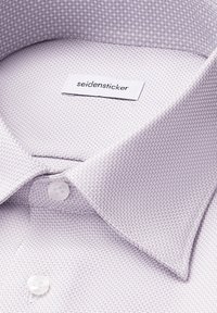 Chemise texturée violet clair avec col boutonné. Dotée d'une étiquette logo et de deux boutons blancs au col.