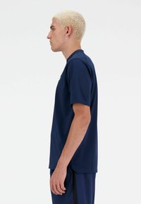 Navy blue short-sleeved athletic shirt with a crew neckline and smooth texture, shown on a model from the side.