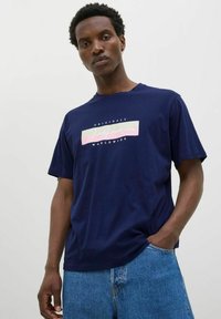 Námorně modré bavlněné tričko s krátkým rukávem, se středovým grafickým designem v světlých barvách, na kterém je nápis "Jack & Jones Originals Worldwide."