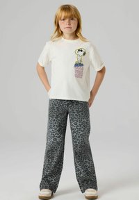 Hvit bomulls-t-skjorte med Snoopy-grafikk i svart og gult. Kombinert med grått, vidt leopardmønstrede bukser med høy midje.