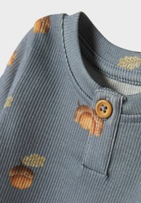 Szara, prążkowana koszula z wzorem żołędzi i liści, okrągłym dekoltem i brązowym guzikiem przy kołnierzu.