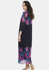 Długa, granatowa sukienka z kwiatowymi wzorami w odcieniach różu i niebieskiego. Luźne, przezroczyste rękawy i dół. Miękka tkanina, długość do kostek, o luźnym kroju.