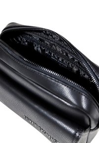 Pochette in pelle nera Armani Exchange con zip, con fodera interna visibile e logo del marchio sul davanti.