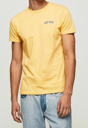 T-shirt en coton jaune avec un col rond, des manches courtes et un petit logo "PEPE JEANS" bleu marine sur la poitrine. Porté avec un jean en denim bleu clair.