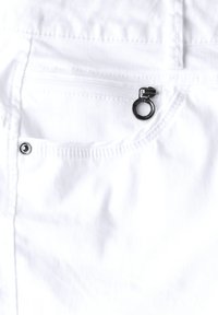 Tela de mezclilla blanca que cuenta con un bolsillo con cierre seguro, con una pestaña de tirón circular negra y un detalle de botón a presión plateado, mostrando una textura suave.
