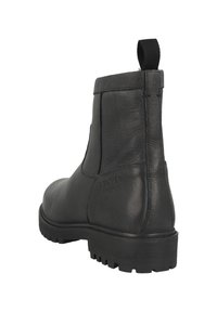 Černá kožená kotníková bota s texturovaným povrchem, elastickými bočními panely a poutkem. Disponuje robustní podrážkou pro lepší přilnavost.