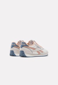 Zapatillas blancas y rosa claro con materiales de malla y gamuza, que presentan acentos azules, un talón reforzado y una suela de goma texturizada.