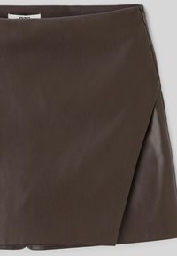 Mini-jupe en cuir marron avec une texture lisse et un design enveloppant, présentant un éclat subtil et des bords nets.