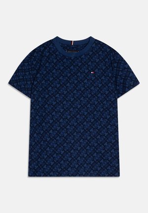 T-shirt à manches courtes bleu marine avec un motif géométrique intégral et un petit logo rouge, blanc et bleu sur la poitrine gauche.