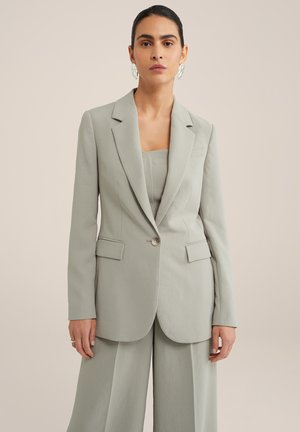 Blazer ajustado verde claro con solapas de muesca y cierre de un solo botón, combinado con una camisola a juego, que destaca por sus líneas limpias y textura suave.