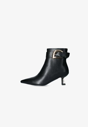 Stivaletto nero in pelle con punta affusolata, dettaglio con fibbia dorata sul cinturino e tacco scultoreo e affusolato. Texture liscia in tutto il prodotto.