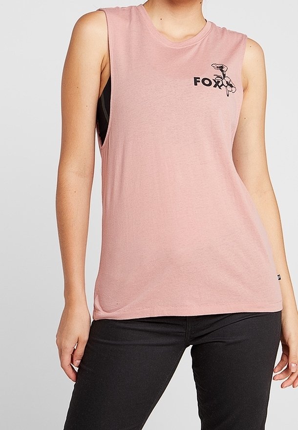 Ärmelloses pinkfarbenes Oberteil mit schwarzem Blumenlogo auf der Brust, getragen zu schwarzen Hosen; Modell mit sichtbar torso und Armen vor einfarbigem Hintergrund.