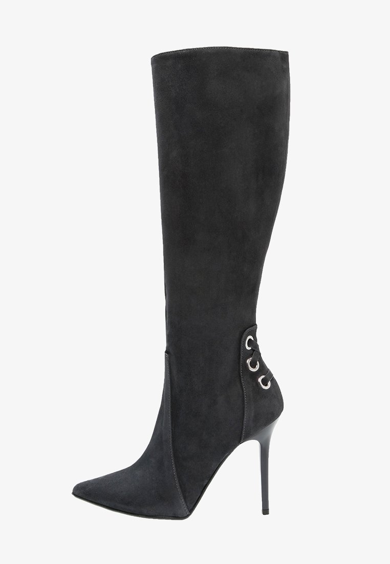 Bota de ante negra por encima de la rodilla con punta afilada, tacón de aguja alto y ojales decorativos en el lateral para detalle de cordones.