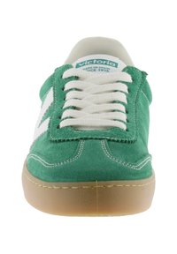 Gröna mockaskor med vita läderstripe på sidorna, beige gummisulor och beige snören. Har en vadderad krage och sydda detaljer.