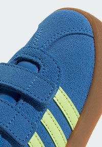 Plave nubuk cipele s smešnim gumenim đonom, dva Velcro remena i tri istaknute neon zelene pruge sa strane.