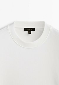 Hvid sweatshirt med rund hals og ribbet krave, lavet af blødt stof. Inkluderer et sort label med mærke- og størrelseoplysninger.