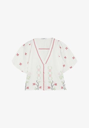 Blusa blanca de manga corta con ribete en zigzag rojo y bordado floral en rojo, verde, rosa y negro, con escote en V y corte amplio.