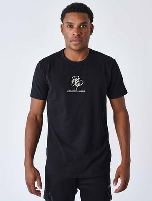 Camiseta de algodón negra con el logo "PROJECT X PARIS" en blanco, de manga corta, corte clásico, textura suave. Combinada con pantalones negros.