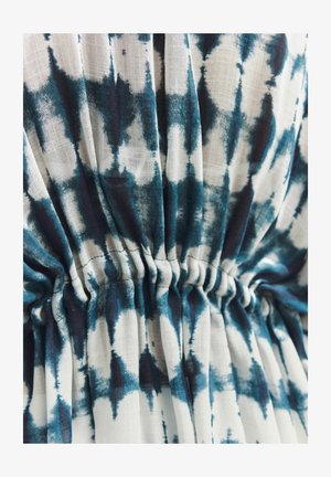 Material din bumbac cu un model tie-dye albastru și alb, cu detalii plisate care creează textură și interes vizual.
