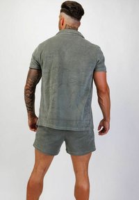 Olivgrön kortärmad polotröja och matchande shorts i mjukt, texturerat tyg, med en avslappnad passform och klassisk krage.