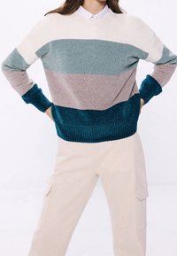 Maglione a righe in maglia con colori: crema, turchese, rosa polveroso e turchese scuro. Polsini e orlo a costine, tessuto testurizzato, vestibilità rilassata.