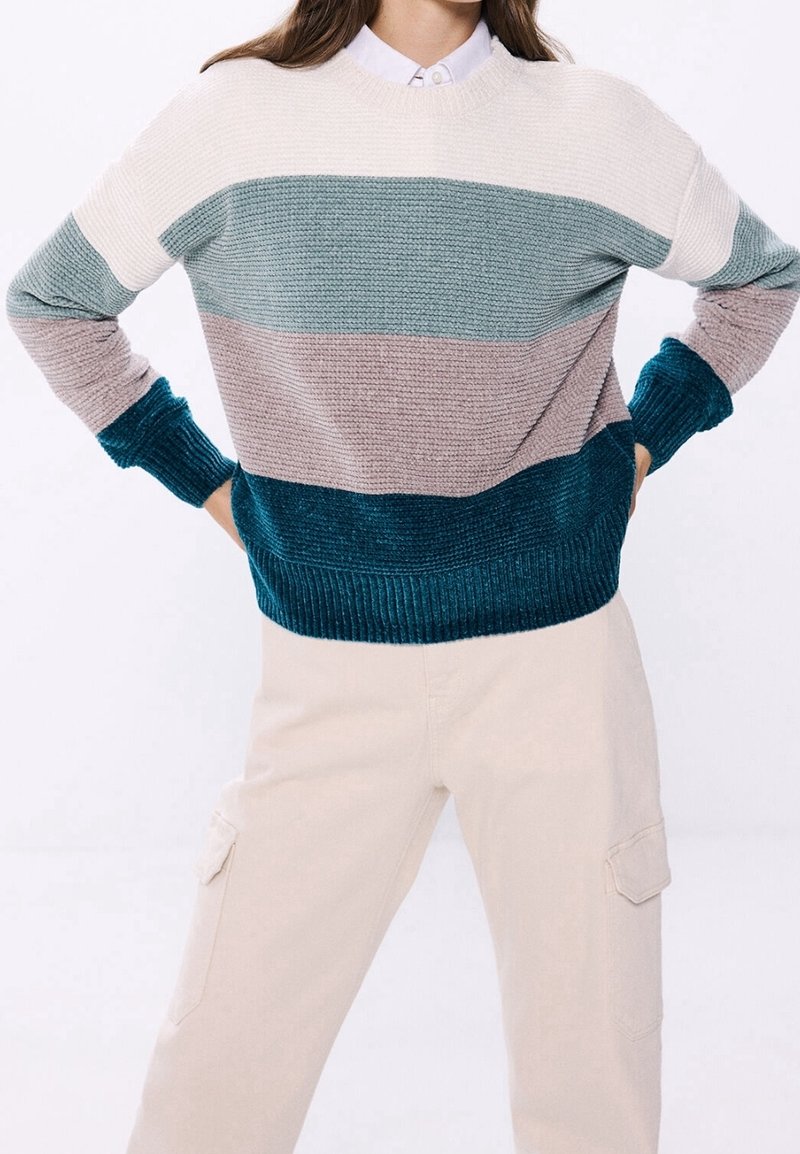 Maglione a righe in maglia con colori: crema, turchese, rosa polveroso e turchese scuro. Polsini e orlo a costine, tessuto testurizzato, vestibilità rilassata.