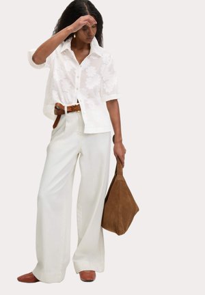 Witte sheer short-sleeve shirt met bloemenpatroon, hoge taille witte wijde broek, bruine riem, bruine suède tas, bruine puntige flats.