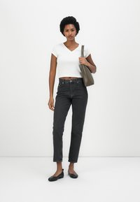 White short-sleeve V-neck top, high-waisted black jeans, black flats, and olive green shoulder bag. Solid colors, casual fit, minimal detailing.
