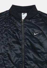 Μαύρο τζάκετ μπομπέρ με επένδυση, με ριχτό γιακά, πλήρη φερμουάρ και μικρό λευκό λογότυπο στο αριστερό στήθος. Μαλακό, γυαλιστερό συνθετικό υλικό.