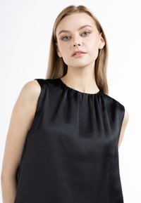 Sort ærmeløs bluse i satin, med en draperet halsudskæring og en glat, skinnefuld tekstur, der fremhæver en afslappet pasform.
