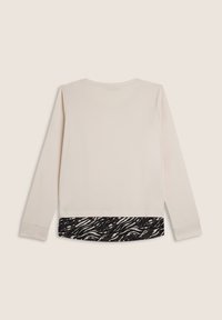 Top a maniche lunghe beige chiaro con orlo inferiore a stampa zebrate bianco e nero. Tessuto morbido con design dritto e colletto girocollo standard.