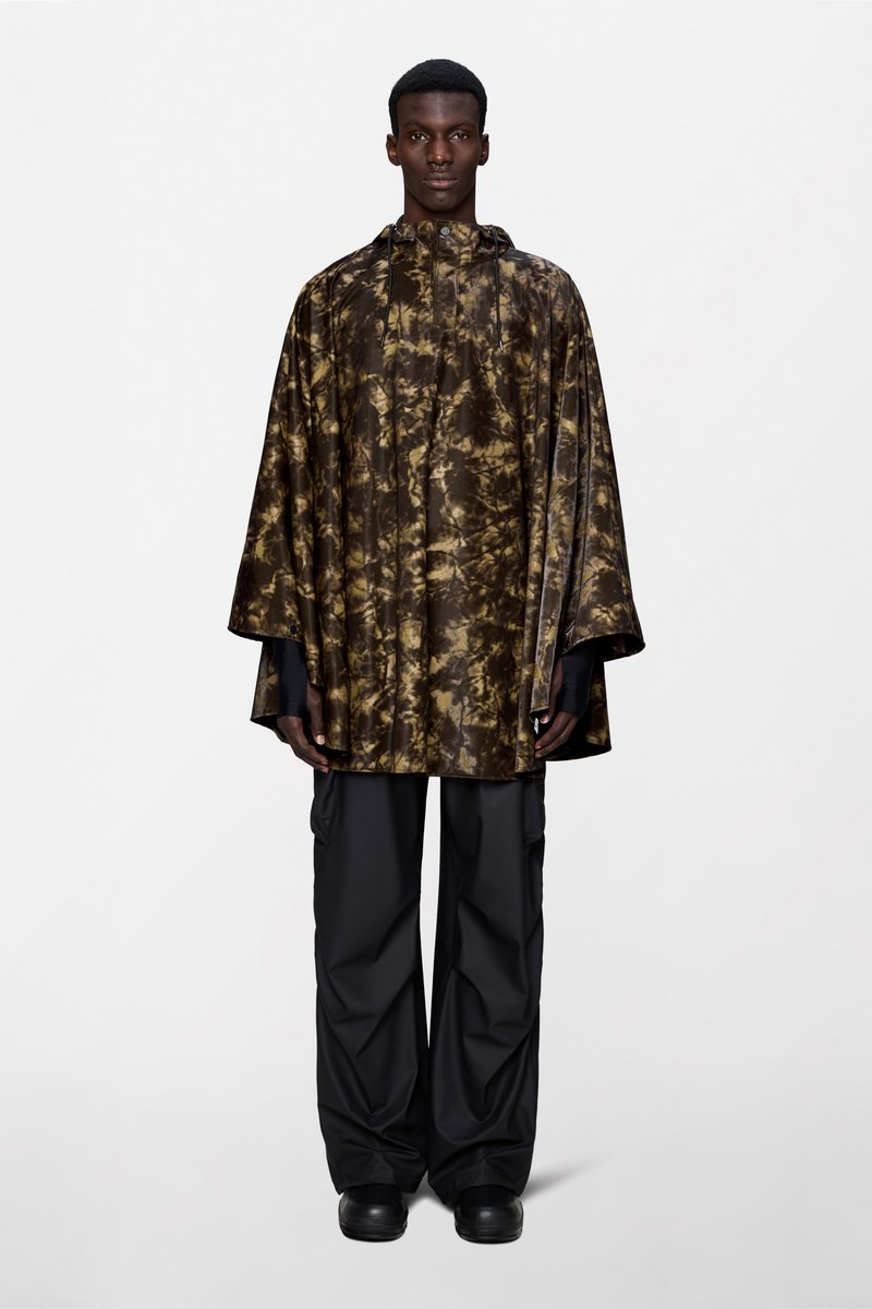 Αδιάβροχο πόντσο με καφέ και μαύρο μοτίβο τύπου tie-dye, με κουκούλα και άνετη εφαρμογή, σε συνδυασμό με υπερμεγέθη μαύρα cargo παντελόνια.