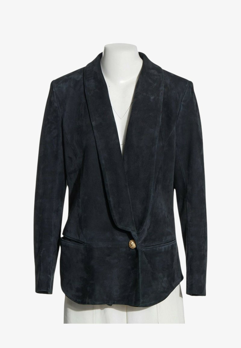 Blazer en daim noir avec larges revers et une fermeture par un bouton doré unique, présenté sur un buste de mannequin blanc.