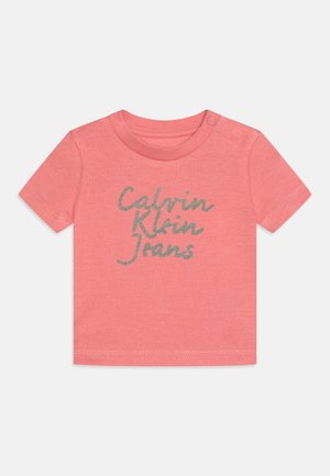 Koralfarvet baby T-shirt med korte ærmer, skulderknap og sølvfarvet "Calvin Klein Jeans" skrift på forsiden.