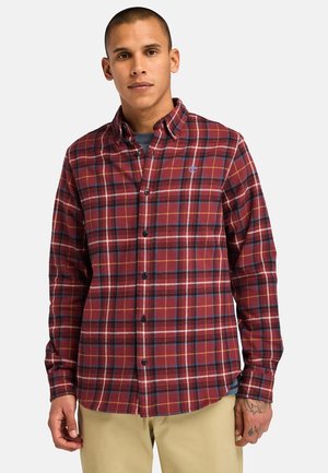 Camisa de franela a cuadros rojos y azules con cuello tipo polo, cierre de botones y dobladillo curvado. Presenta mangas largas y un pequeño logotipo en el pecho.
