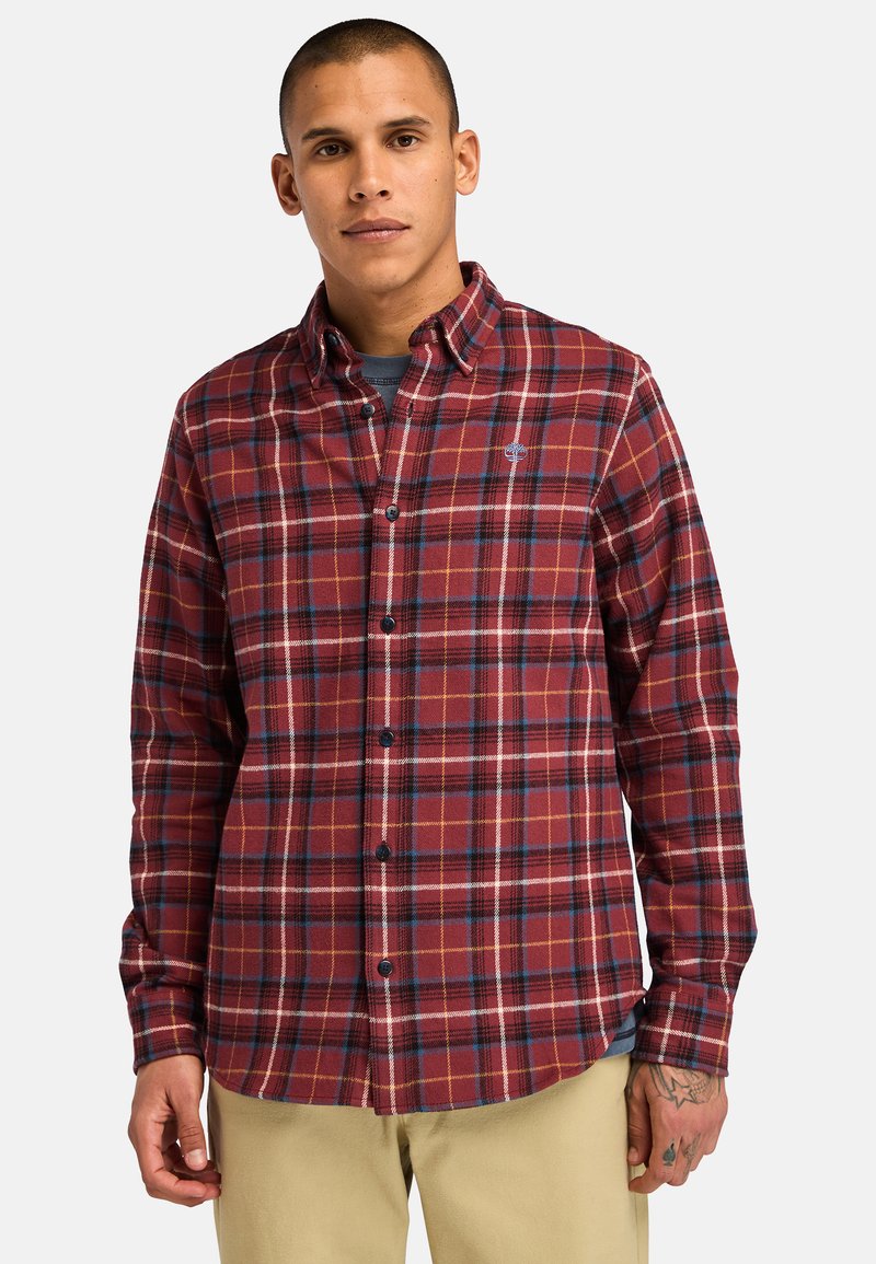 Camicia in flanella a quadri rossi e blu con colletto, chiusura a bottoni e orlo curvo. Presenta maniche lunghe e un piccolo logo sul petto.