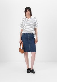 Stripete hvit og marineblå t-skjorte, blå denim skjørt til kneet, svarte loafers og liten brun håndveske. Glatte teksturer, avslappet passform.