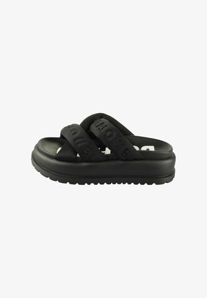 Zwarte platte sandalen met twee dikke, gekruiste banden met reliëfbranding, een gestructureerde zool voor grip en een minimalistisch ontwerp.