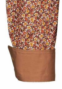 Manica di camicia floreale con sfondo marrone e fiori gialli, arancioni e bianchi. Il polsino è di un marrone uniforme, realizzato in un tessuto liscio.