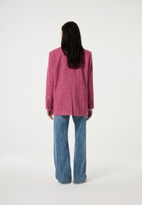 Roze tweed blazer met een rechte snit, lange mouwen en twee knopen op de manchetten, gecombineerd met wijde blauwe jeans.