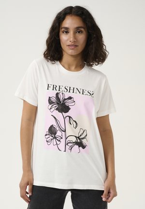 T-shirt en coton blanc avec un imprimé graphique de fleurs noires sur un fond rose, avec le texte "FRESHNESS?" en gras.