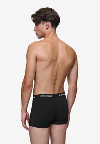 Črne boxer boksarice iz mehkega materiala s prilegajočim dizajnom in elastičnim pasom, ki nosi belo oznako "PEGADOR".
