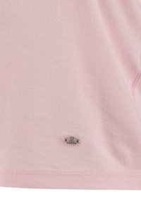 T-shirt en coton rose clair avec une texture douce, des manches courtes et une étiquette en métal argenté avec "LARGO" au bas.