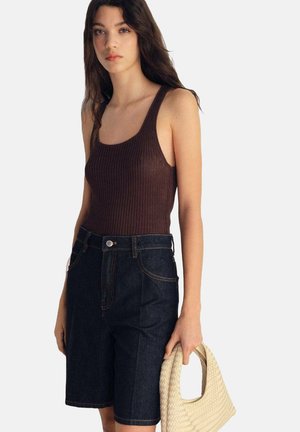 Brun ribbet tanktop parret med højttaljede mørke denimshorts, holdt sammen med en vævet beige håndtaske. Enkel design og tætsiddende silhuet.