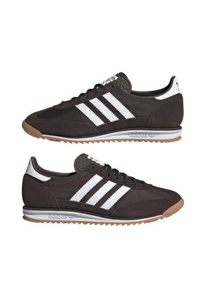 Baskets en suede marron avec un design à trois bandes blanches, des accents texturés sur la languette, une semelle en caoutchouc et un branding minimaliste au talon.