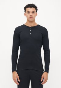 Crna dugorukašna henley majica od rebrastog materijala, s okruglim izrezom, plaketom s tri dugmeta i prilagođenim krojem.